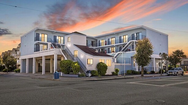 A modern multi-story building with a flat roof, multiple balconies, and a staircase leading to the upper floors.