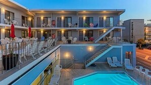 A hotel with a pool area, outdoor seating, and multiple balconies.