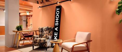 Un espace de détente moderne comprenant un canapé, un fauteuil et une table sur laquelle est posée une pancarte indiquant : « FAITES-VOUS ENTENDRE ».