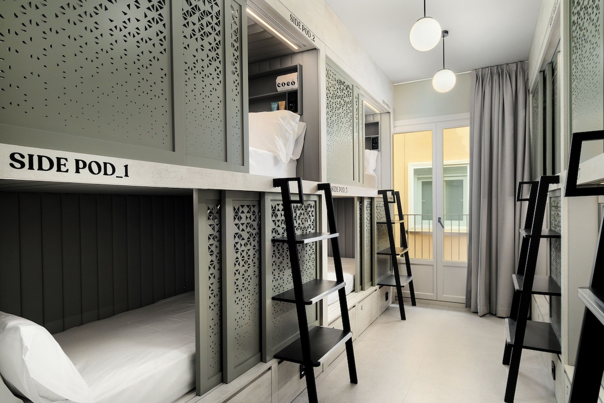 Een moderne hotelkamer met stapelbedden, een ladder en een klein bureau.