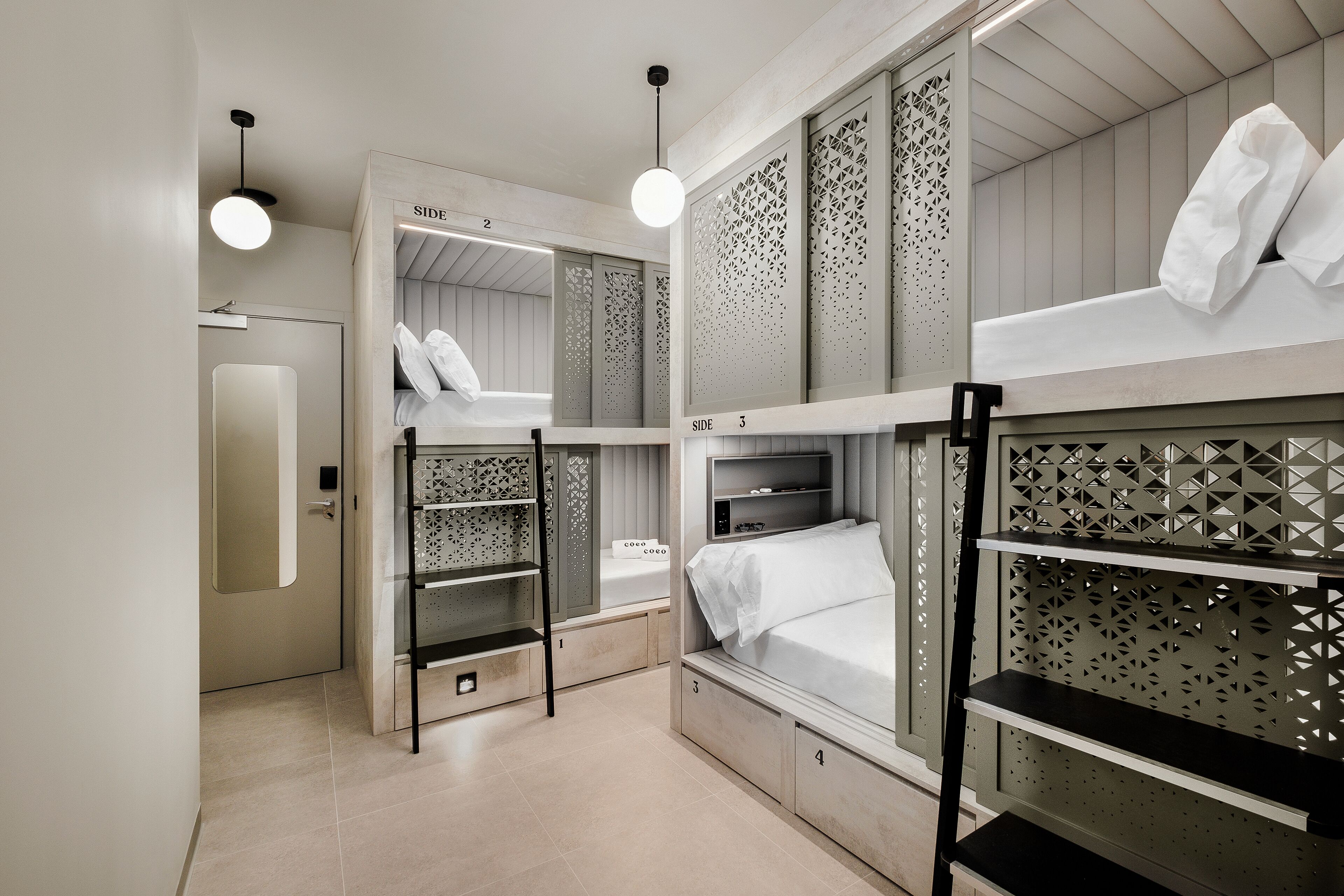 Habitación con literas, una cama al lado de la otra, una estantería y una puerta.