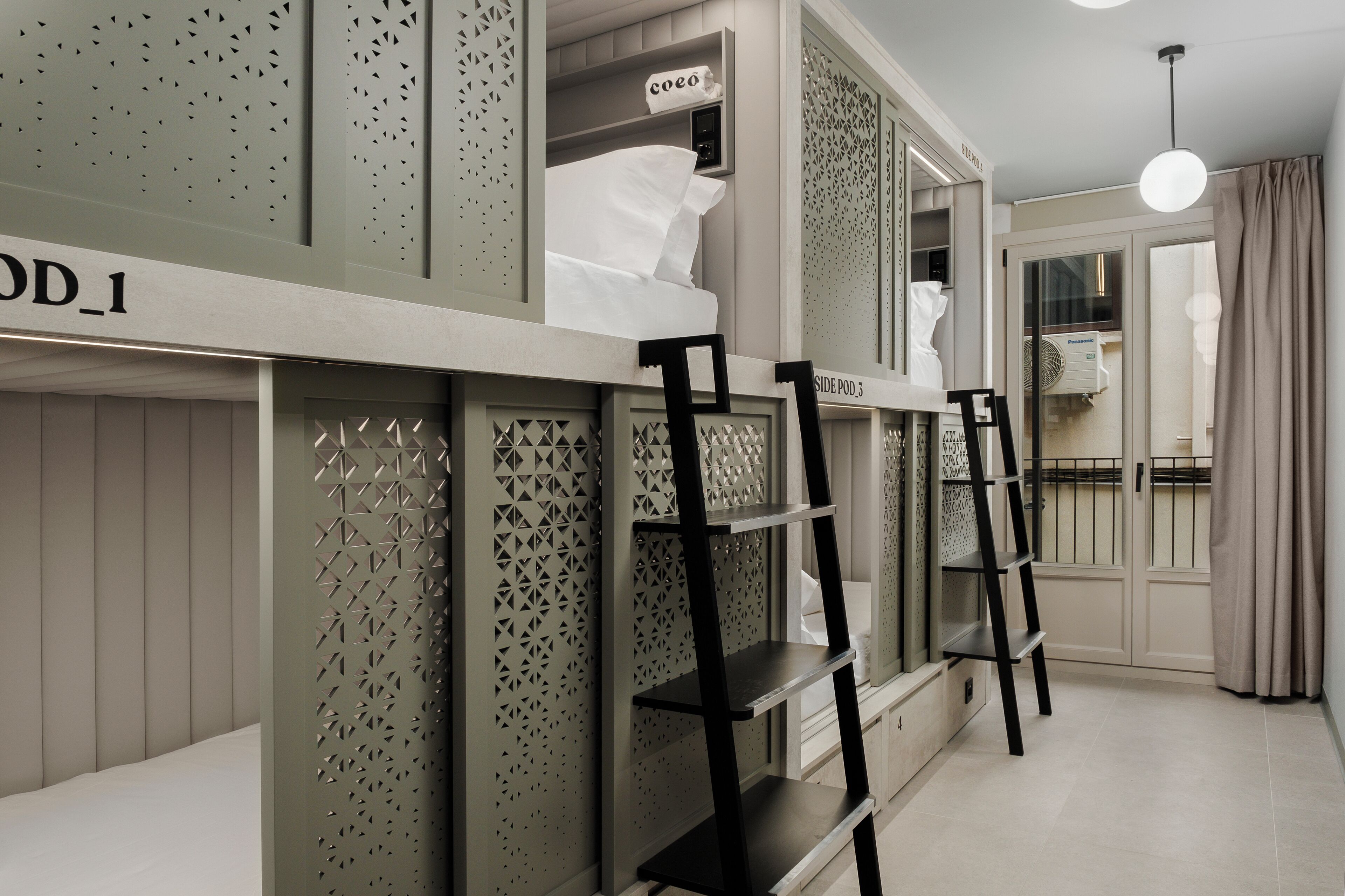 A bunk bed with a ladder, a shelf unit, and a small window with a curtain.
