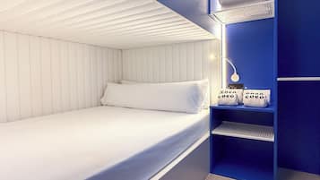 A bedroom with a bed, a nightstand, and a shelf with towels.