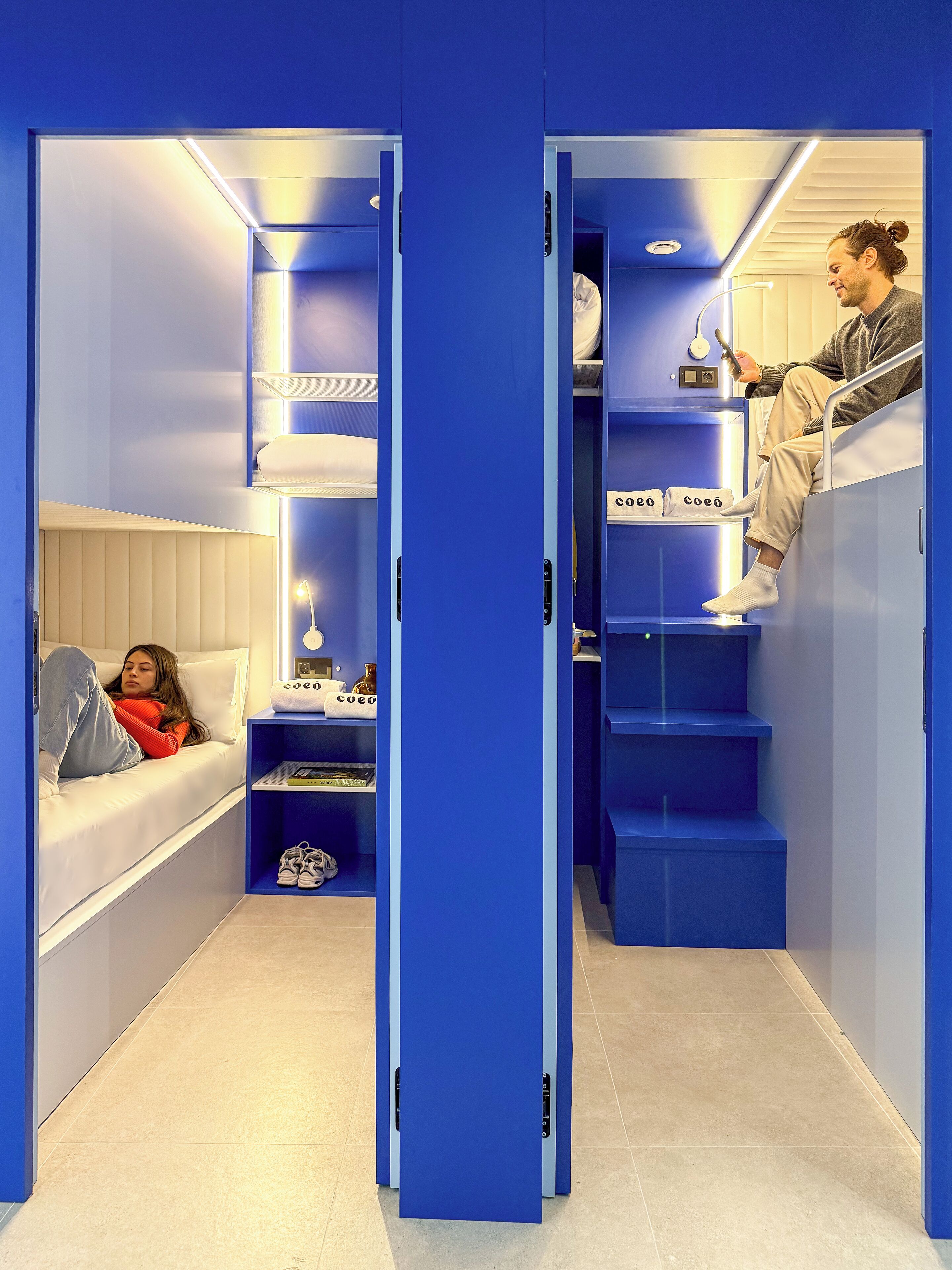 Una habitación compacta con cama, un rincón de descanso y una escalera que sube a un altillo.