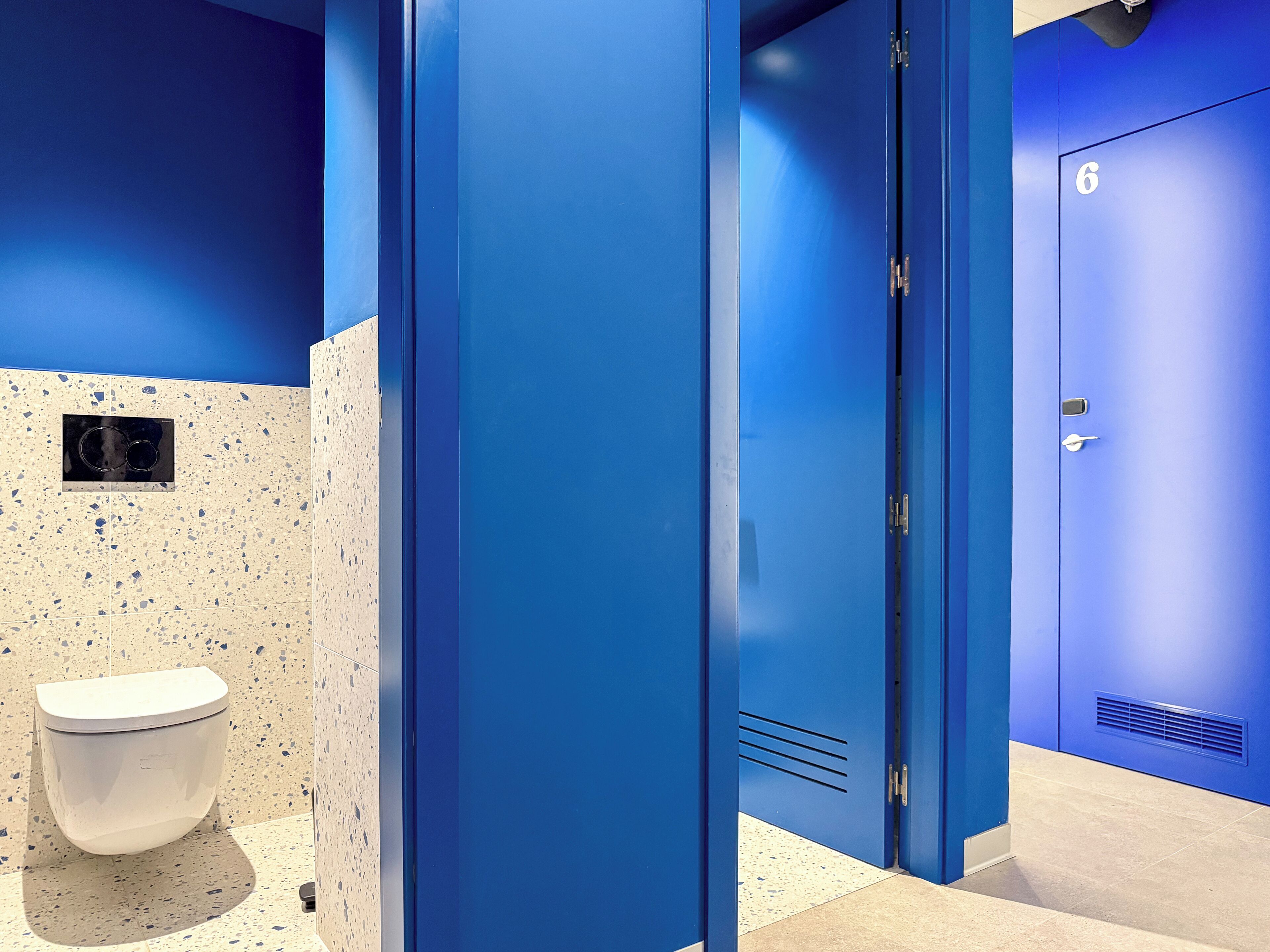 A restroom with blue doors, a white toilet, and a speckled wall.