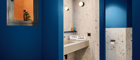 A bathroom with a blue and white speckled tile design, a white sink, and a towel rack with towels labeled "coeo".