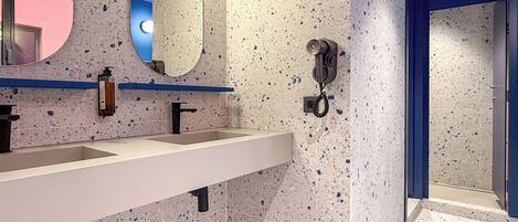 A modern bathroom with a white sink, a mirror, and a telephone.