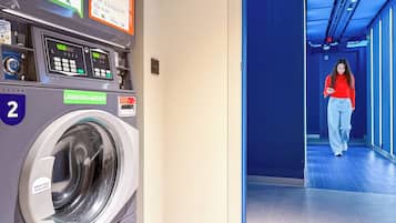 A public laundromat with a washing machine, a control panel, and a sign indicating a 4.00 euro fee.