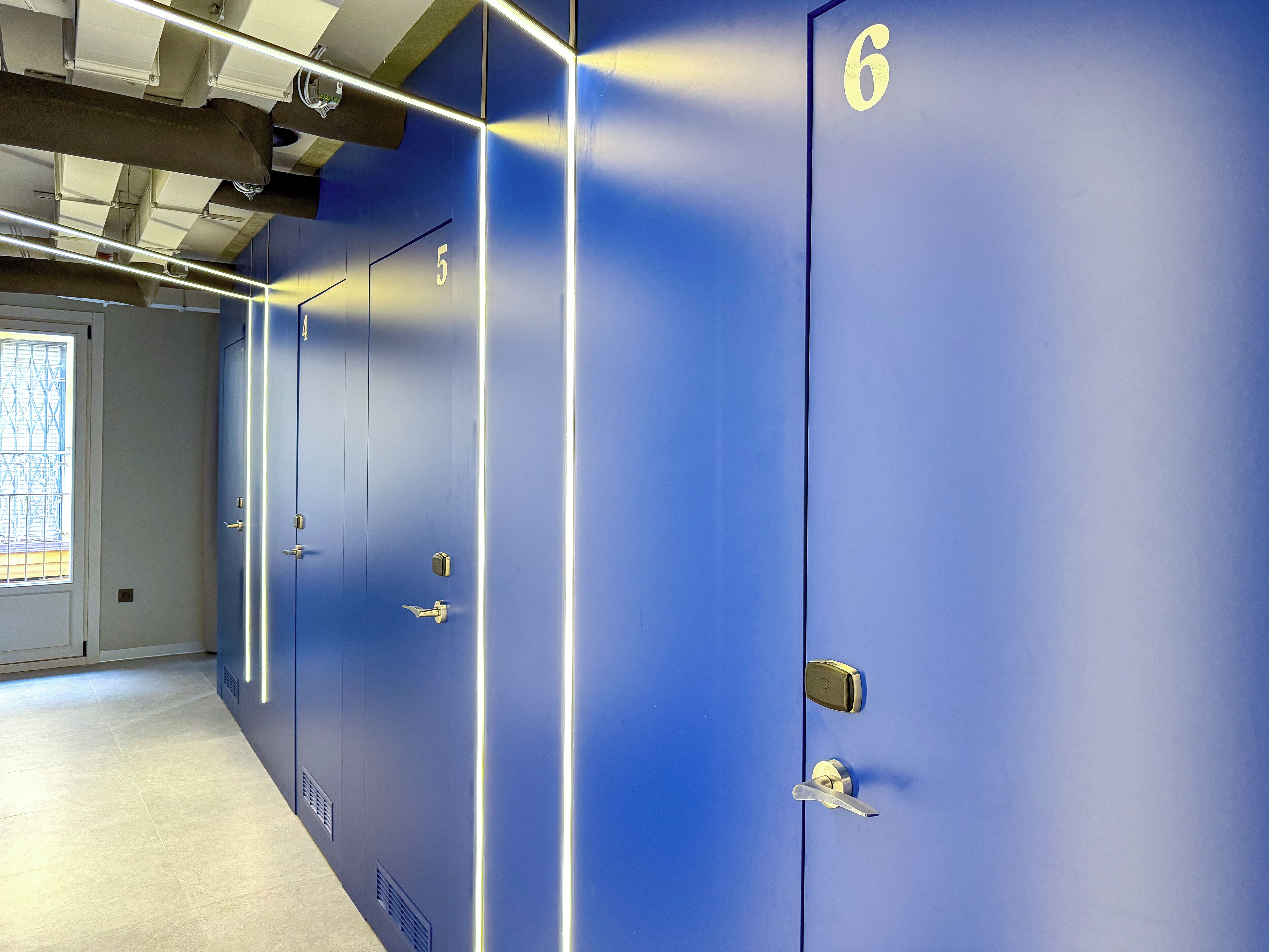 A row of blue lockers numbered 4 to 6 in a hallway with a tiled floor and a window with a grid pattern.