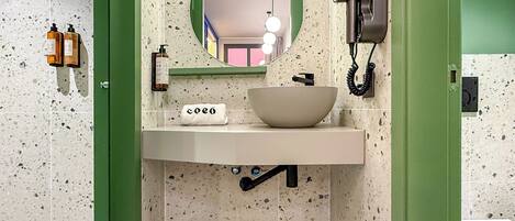 A bathroom with a white sink, a bowl, a mirror, and a hairdryer.