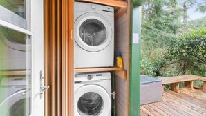 A laundry room with two washing machines and a bottle of detergent on a shelf.