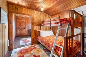A wooden cabin room with a bunk bed, a ladder, and a door leading outside. - Oceanside w/Views, Dog-Friendly, Gas Stove (Oceanside)