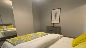 Een hotelkamer met een bed, nachtkastje, lamp en een ingelijst schilderij aan de muur.