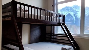 A bunk bed in a room with a large window, carpeted floor, and a ceiling light. - rent comfort in canmore - central to everything (Canmore)