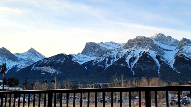 A mountain range with snow-covered peaks and a parking lot in the foreground. - rent comfort in canmore - central to everything (Canmore)