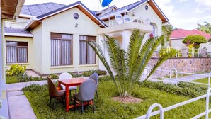 A two-story house with a balcony, a satellite dish, and a small garden with a palm tree. - Emerald Villa Cafe & Restaurant (Kigali)
