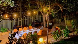 An outdoor dining area with tables set for two, surrounded by chairs and plants. - Emerald Villa Cafe & Restaurant (Kigali)