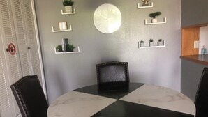 Uma sala de jantar com uma mesa redonda, cadeiras de couro preto e um relógio de parede.