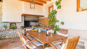 A wooden dining table with six chairs, a stone wall, a fireplace, and a hanging plant.