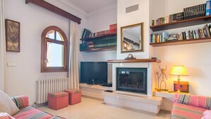 A cozy living room with a fireplace, a television, and a bookshelf.
