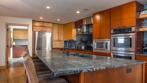 A modern kitchen with a large island, stainless steel appliances, and wooden cabinetry. - Luxe Lakefront Estate near Minneapolis, Hot Tub, Sauna, Kayaks, Sleeps up to 20 (Baldwin)