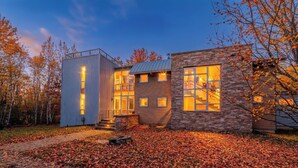 A modern house with a large window and a stone facade. - Luxe Lakefront Estate near Minneapolis, Hot Tub, Sauna, Kayaks, Sleeps up to 20 (Baldwin)
