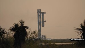 A launch tower with a rocket on the pad, surrounded by palm trees.