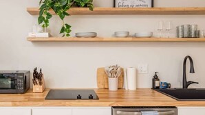 Una cocina moderna con estantes de madera, microondas, lavabo y lavavajillas.