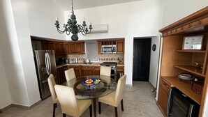 Una cocina moderna con armarios de madera, una mesa de comedor de vidrio y una araña.