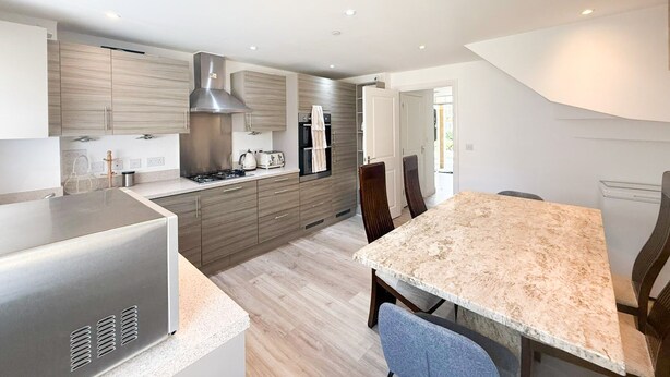 A modern kitchen with a central island, stainless steel appliances, and wooden cabinetry. - Your Bromley Experience  (Bromley)