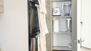 A kitchen with a built-in oven, a coffee maker, and a blender on the countertop. - Your Bromley Experience  (Bromley)