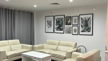Una sala moderna con un sofá modular, una mesa de centro e impresiones botánicas enmarcadas en la pared.