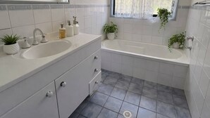 Un bagno con lavandino, specchio e finestra con tende.