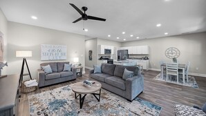 A spacious living room with a grey sofa, a coffee table, and a dining area with a table and chairs. - 4-bedroom Chalet Overlooking Pickwick Landing Golf Course (Counce)