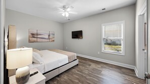 A bedroom with a bed, a ceiling fan, a TV, a window with blinds, and a nightstand with a lamp. - 4-bedroom Chalet Overlooking Pickwick Landing Golf Course (Counce)