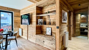 En modern inredning med träpanel, en matplats med stolar och ett bord samt ett köksområde med en diskho och en bänkskiva.