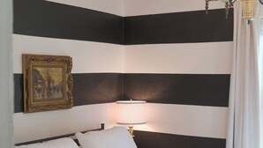 Een hotelkamer met een bed, een schilderij aan de muur, een lamp en een kroonluchter.