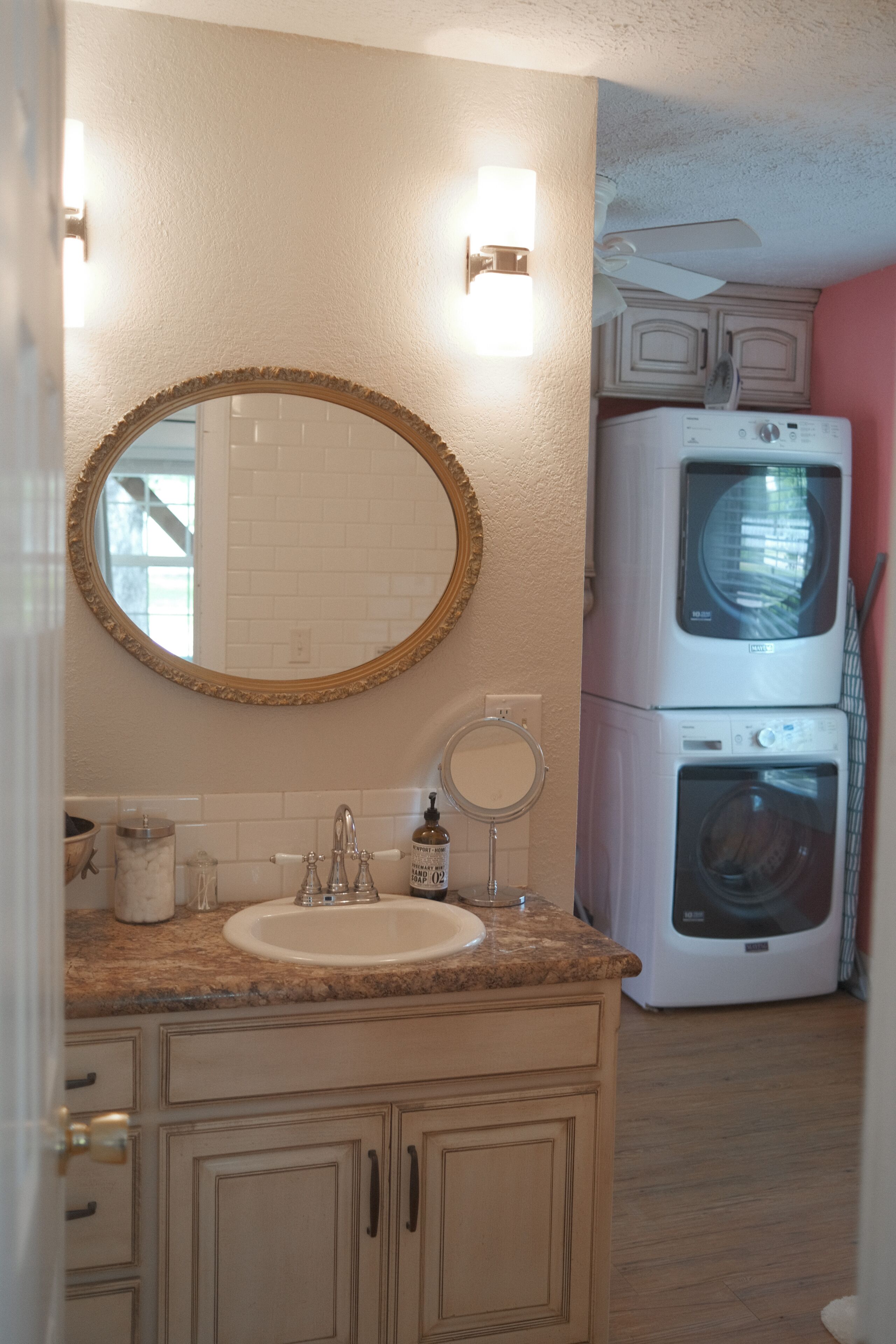 A bathroom with a sink, mirror, and stacked washer and dryer.