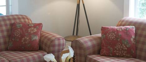 A living room with a round coffee table, two plaid sofas, a mirror, and a floor lamp.