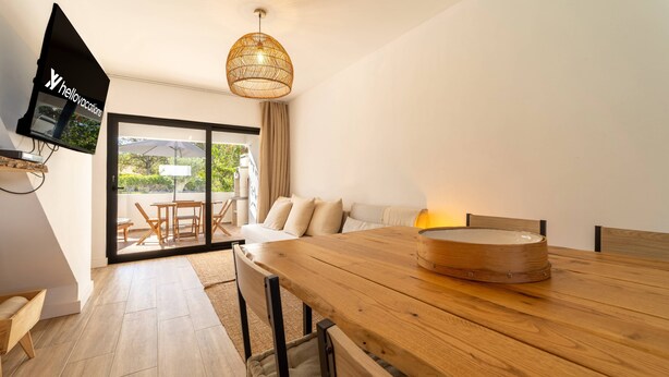 A modern room with a wooden dining table, a sofa, and a television mounted on the wall.