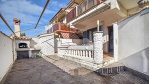 Une cour étroite, pavée de pierres, avec un mur en pierre et un balcon en bois.