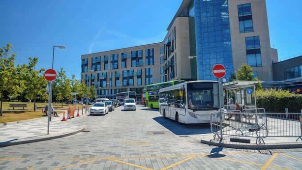 A modern building with a glass facade, a bus stop, and a no-entry sign. - Large 6-Bed House | 2 Bathrooms | Parking | Garden (Bristol)