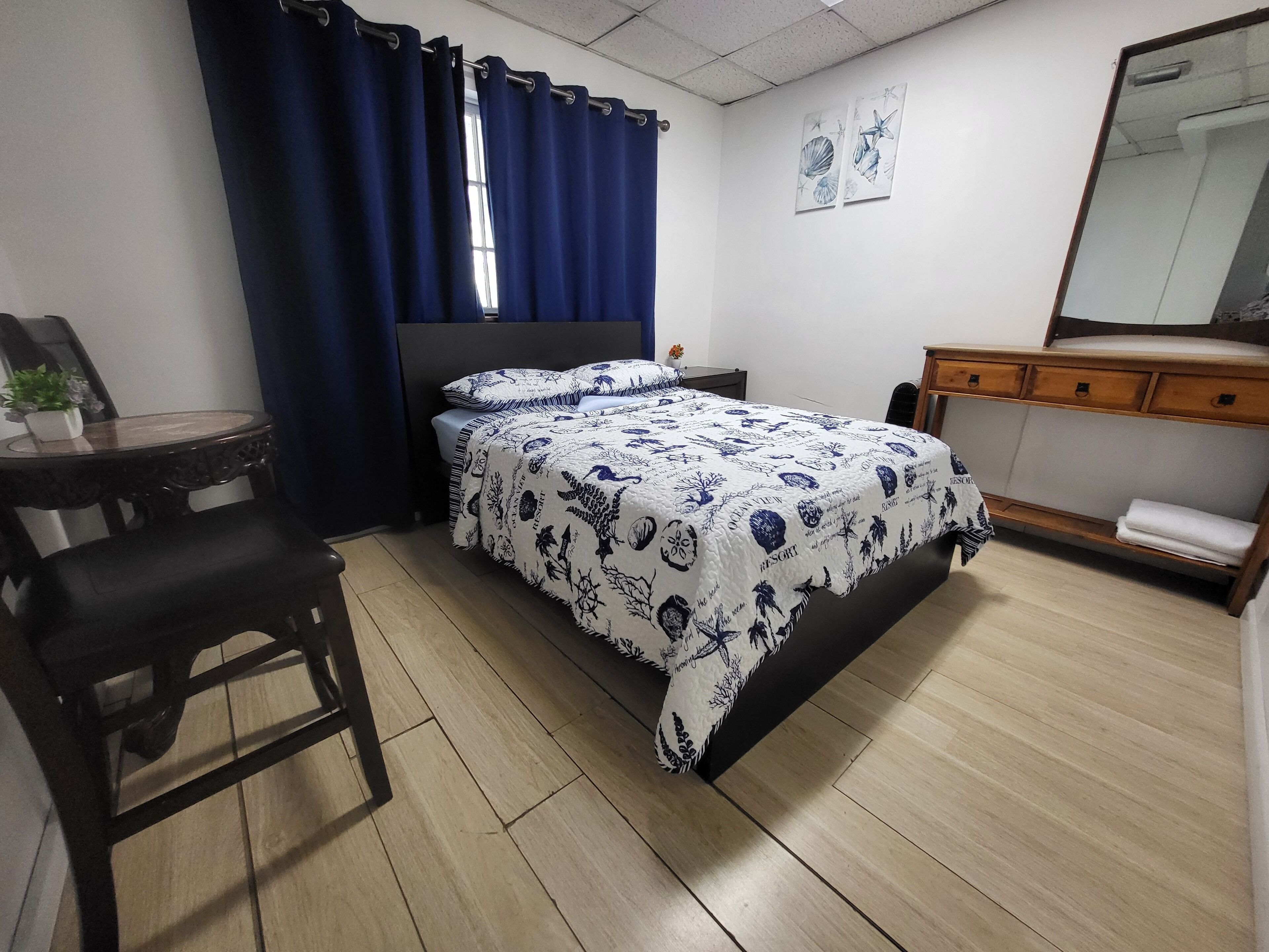 Une chambre à coucher comprenant un lit, un bureau, une chaise, une commode et un miroir.