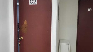 Een kamer met een gesloten deur met de aanduiding 'C2', een klein wit tafeltje en een beige bank.