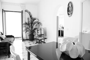 Uma sala de estar com sofá, mesa de centro, planta em vaso e televisão.