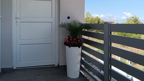 A white door with a keyhole, a white planter with pink flowers, and a grey balcony railing. - 1 bedroom beautiful apartment in Vir (Vir)