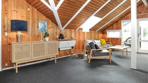 A cozy room with wooden walls, a sloped ceiling, a sofa, a small table, a cabinet, and a window. - 3 bedroom amazing home in Toftlund (Toftlund)