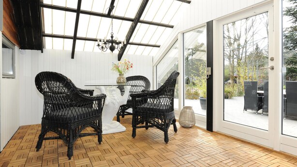A room with a herringbone wooden floor, a glass door leading outside, and two wicker chairs. - 3 bedroom amazing home in Toftlund (Toftlund)