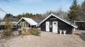 A building labeled 'LYKKEBO' with a sloped roof, a door, and two white urns with flowers in front. - 3 bedroom amazing home in Toftlund (Toftlund)