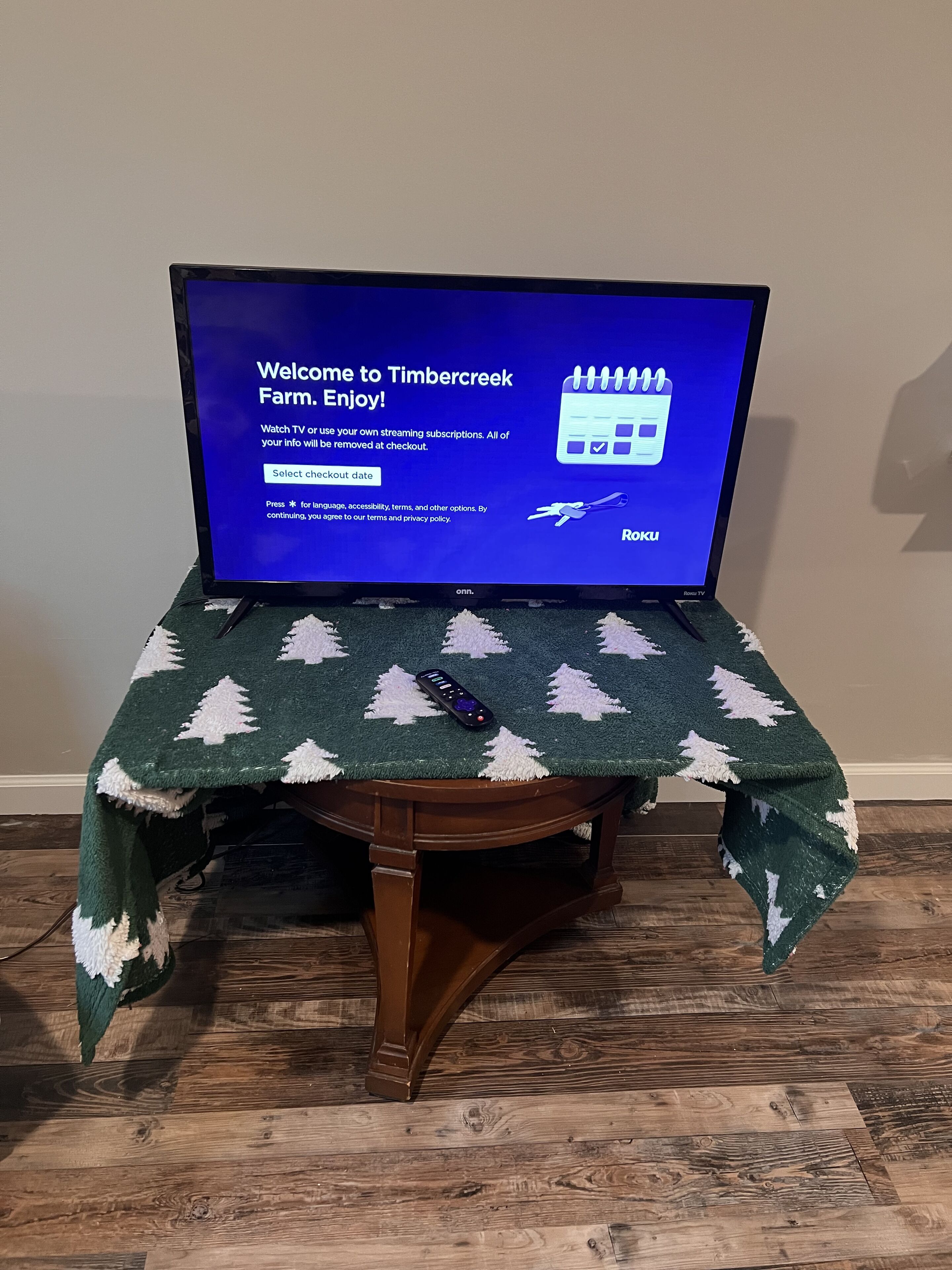 Un televisor sobre una mesa de madera con mantel navideño.